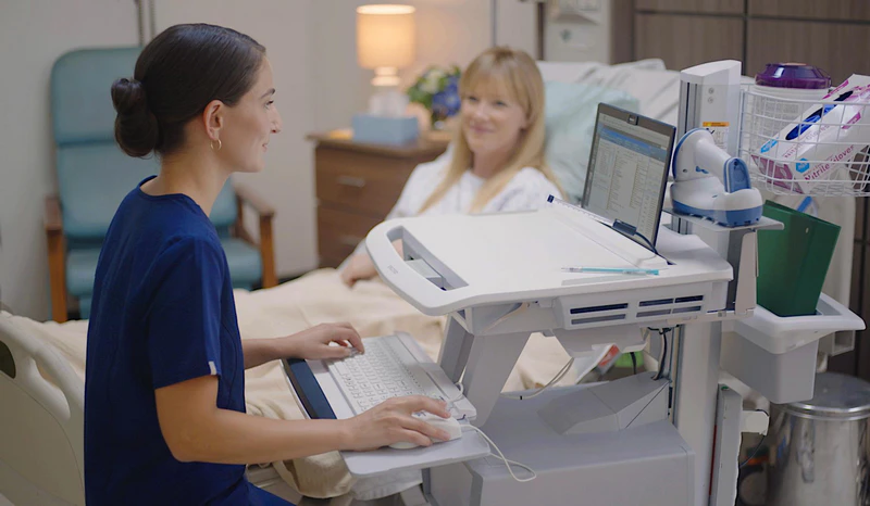 Nurse using a medical computer cart at bedside